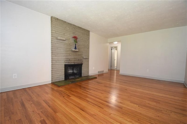 unfurnished living room with light hardwood / wood-style floors, a textured ceiling, and a fireplace