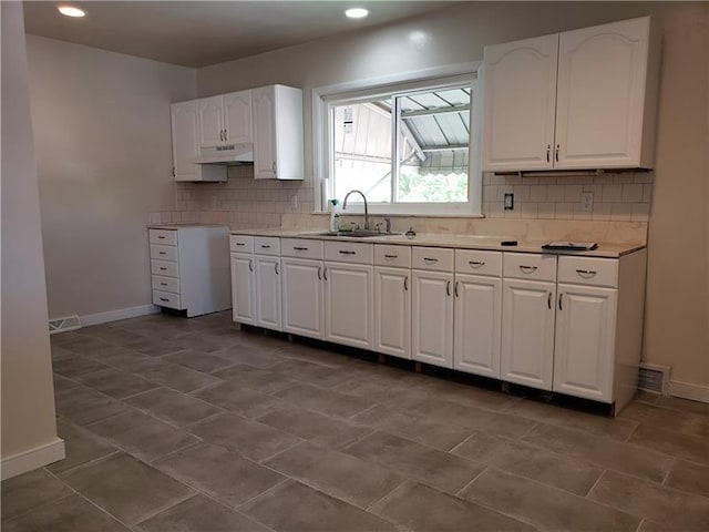 kitchen featuring backsplash, dark tile flooring, white cabinetry, and sink