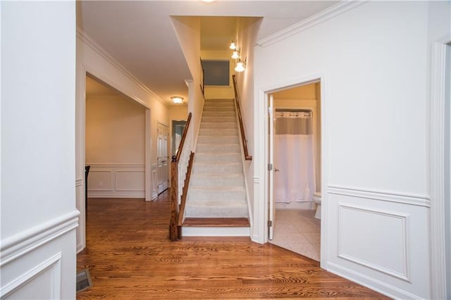 stairway with wood-type flooring and ornamental molding