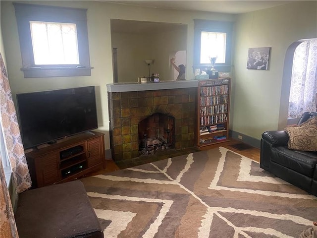 living room featuring a tiled fireplace and dark hardwood / wood-style flooring