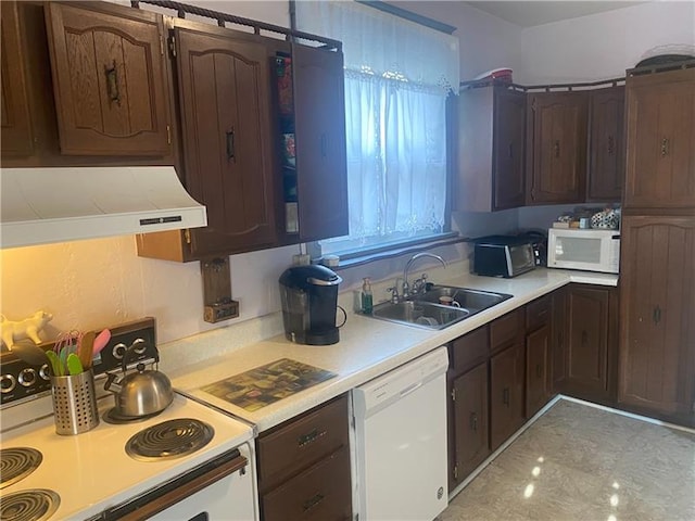 kitchen with custom range hood, dark brown cabinets, white appliances, and sink