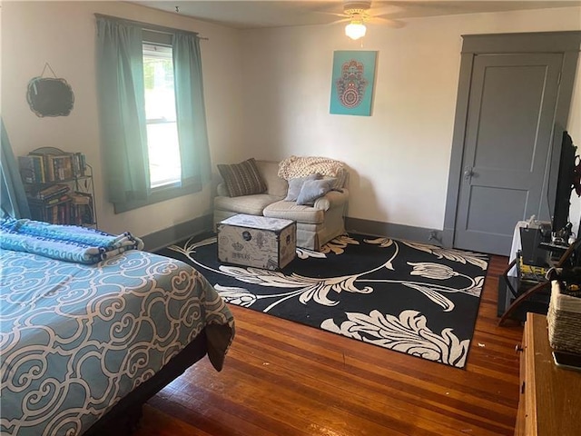 bedroom featuring dark hardwood / wood-style flooring, ceiling fan, and multiple windows