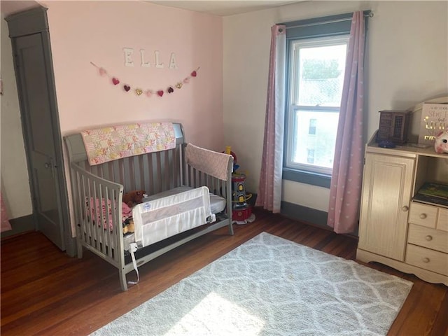 bedroom with dark hardwood / wood-style flooring and a crib