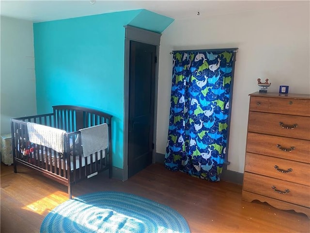 bedroom featuring a crib and dark hardwood / wood-style floors