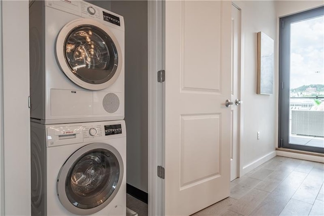 laundry area featuring stacked washing maching and dryer, a healthy amount of sunlight, and light hardwood / wood-style floors