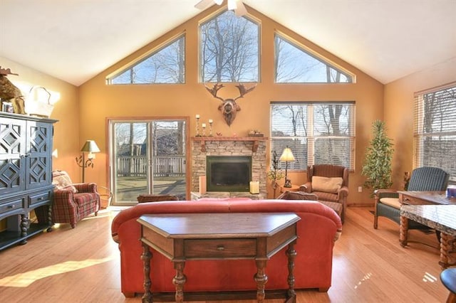 living room with a stone fireplace, high vaulted ceiling, and light wood-type flooring