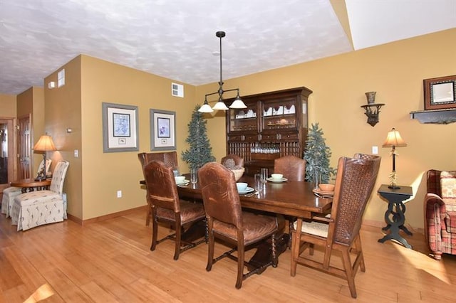 dining area with a textured ceiling and light wood-type flooring