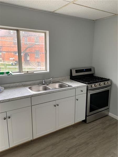 kitchen featuring white cabinets, light hardwood / wood-style flooring, stainless steel range with gas stovetop, and sink