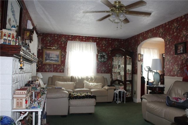 carpeted living room with a textured ceiling and ceiling fan