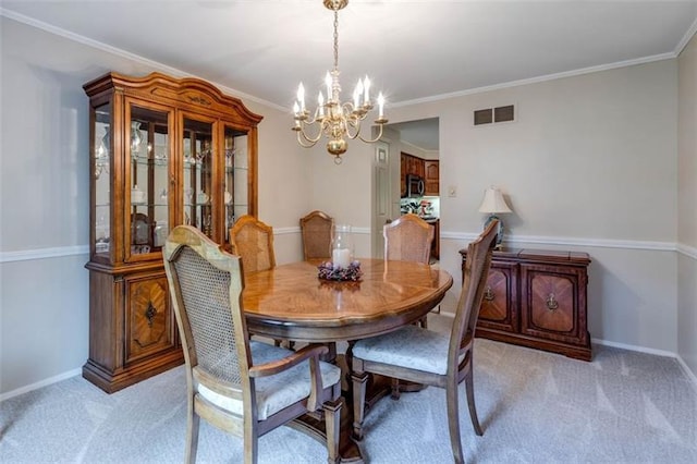 carpeted dining space with a chandelier and ornamental molding