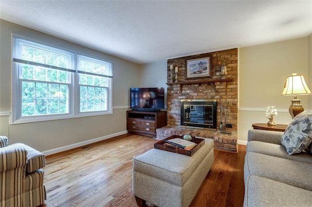 living room featuring brick wall, wood-type flooring, and a fireplace