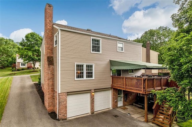 rear view of property with a deck and a garage