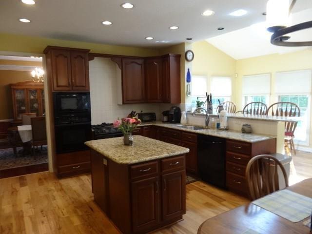 kitchen featuring a notable chandelier, a healthy amount of sunlight, black appliances, and sink