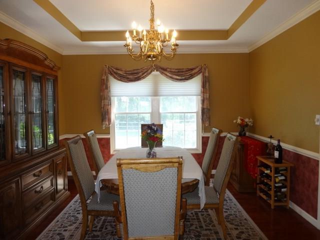 dining room featuring dark hardwood / wood-style flooring, a raised ceiling, ornamental molding, and a chandelier