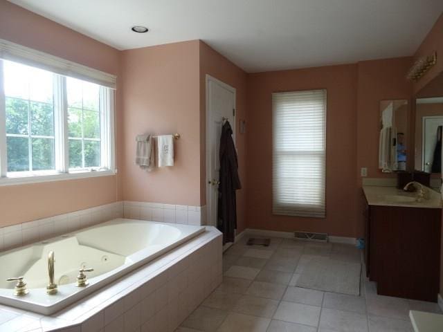 bathroom featuring tile flooring, vanity, and tiled tub