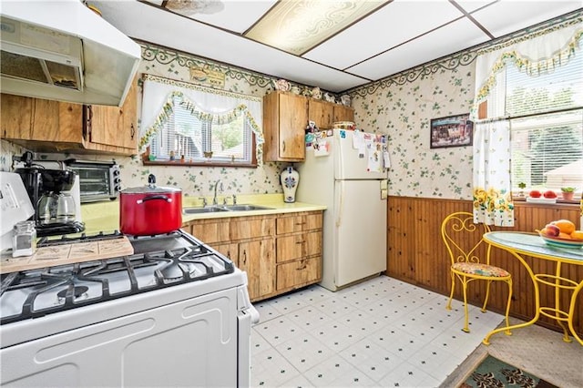 kitchen featuring sink, white appliances, wall chimney range hood, and plenty of natural light