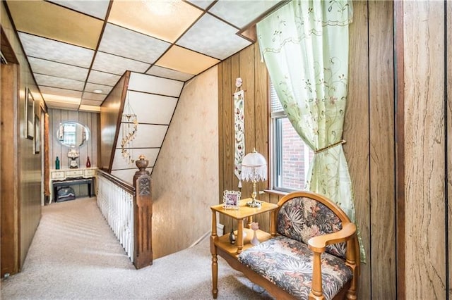 living area featuring wood walls, carpet, and a paneled ceiling