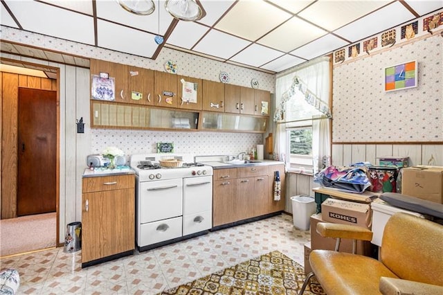 kitchen featuring gas range gas stove, light tile floors, and sink