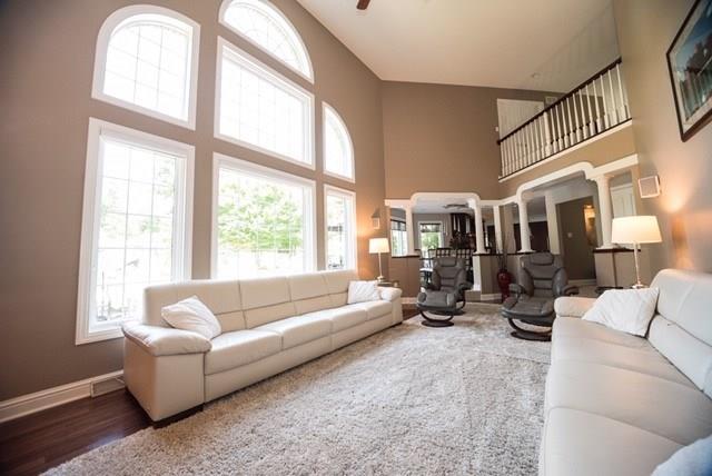 living room with a high ceiling, ceiling fan, and dark wood-type flooring