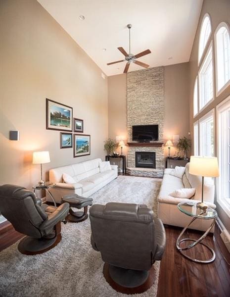 living room with high vaulted ceiling, dark hardwood / wood-style floors, a fireplace, and ceiling fan