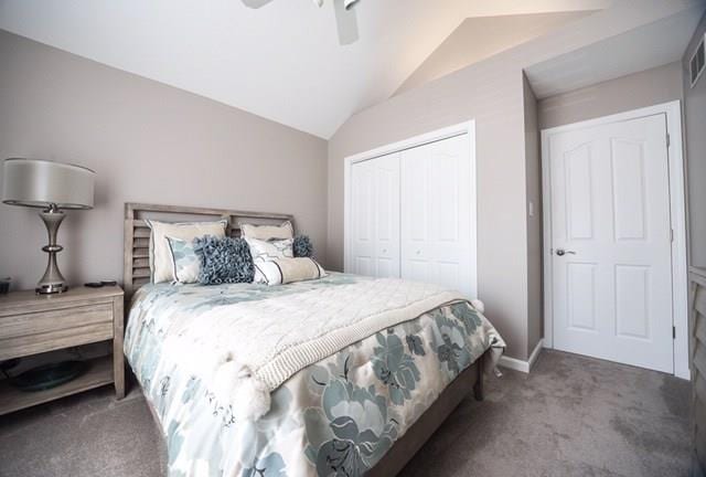 bedroom featuring ceiling fan, a closet, dark carpet, and lofted ceiling