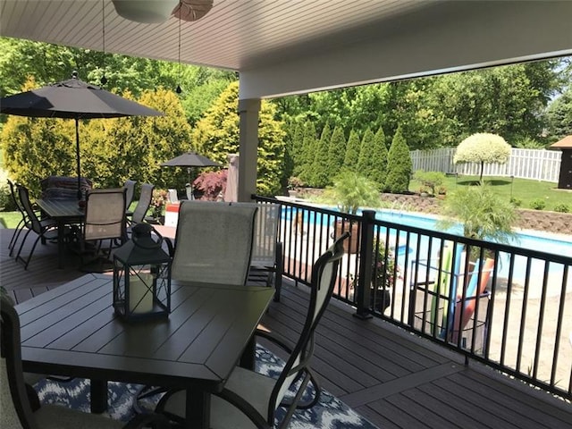 wooden terrace featuring ceiling fan and a fenced in pool