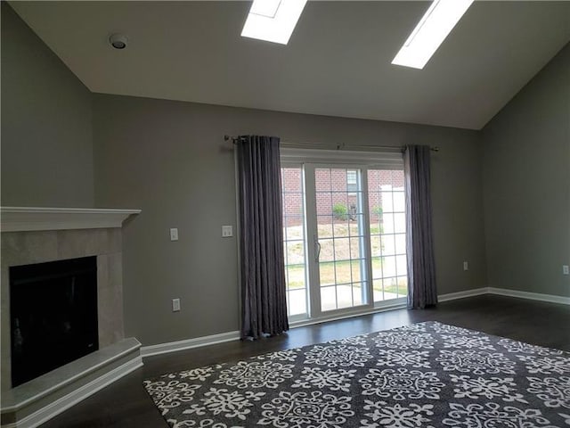 unfurnished living room with lofted ceiling with skylight, dark hardwood / wood-style flooring, and a tile fireplace