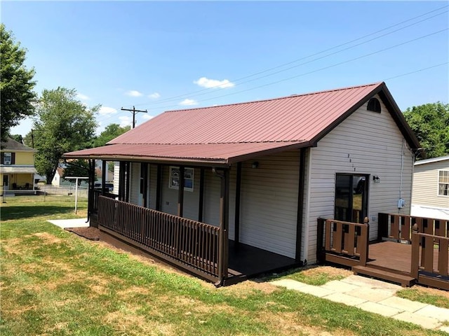 rear view of property featuring a lawn and a deck