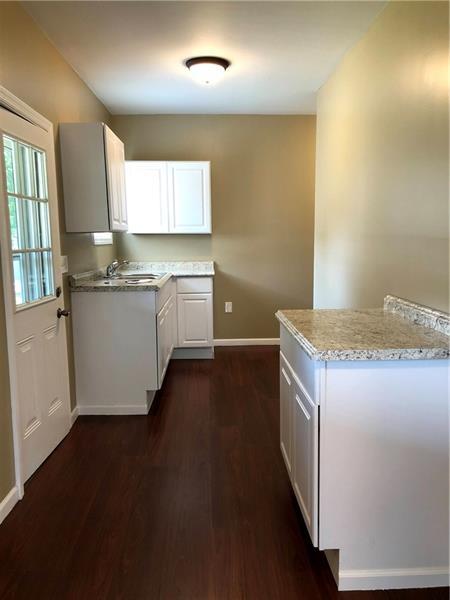 kitchen with white cabinets, dark hardwood / wood-style floors, light stone counters, and sink