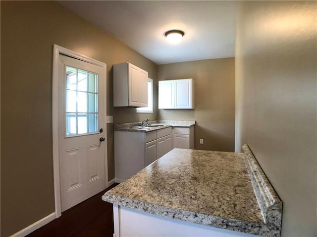 kitchen featuring sink, white cabinetry, dark wood-type flooring, and light stone counters