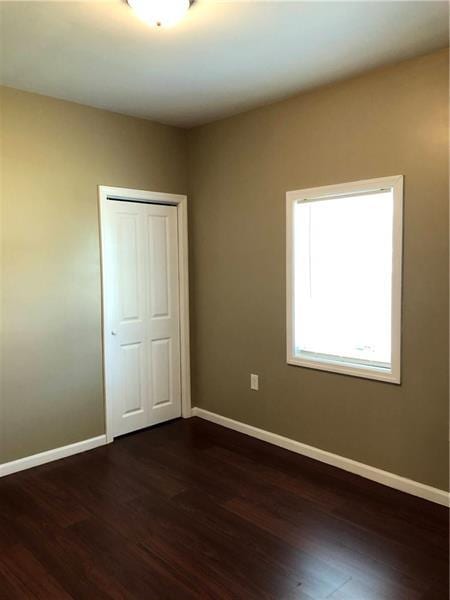 unfurnished bedroom featuring a closet and dark wood-type flooring