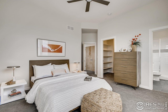 carpeted bedroom featuring ceiling fan, a spacious closet, ensuite bath, and a closet