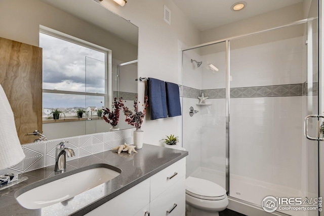 bathroom with an enclosed shower, vanity, tasteful backsplash, and toilet