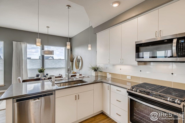 kitchen featuring sink, white cabinetry, stainless steel appliances, decorative light fixtures, and kitchen peninsula