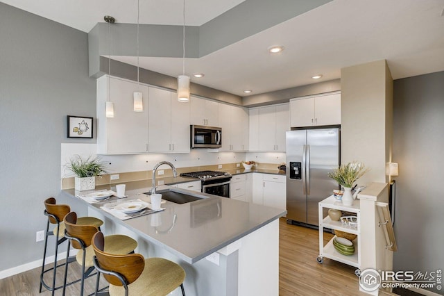 kitchen featuring stainless steel appliances, white cabinetry, kitchen peninsula, and decorative light fixtures