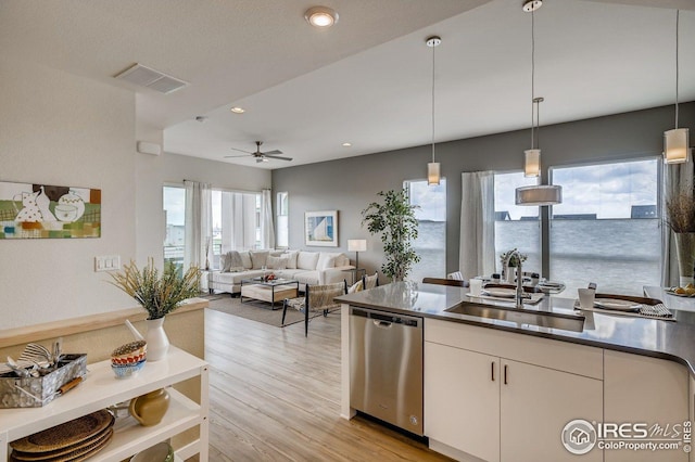 kitchen with pendant lighting, white cabinetry, sink, stainless steel dishwasher, and light hardwood / wood-style floors