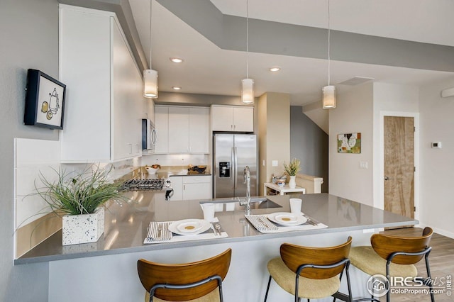 kitchen featuring white cabinetry, tasteful backsplash, hanging light fixtures, kitchen peninsula, and stainless steel appliances