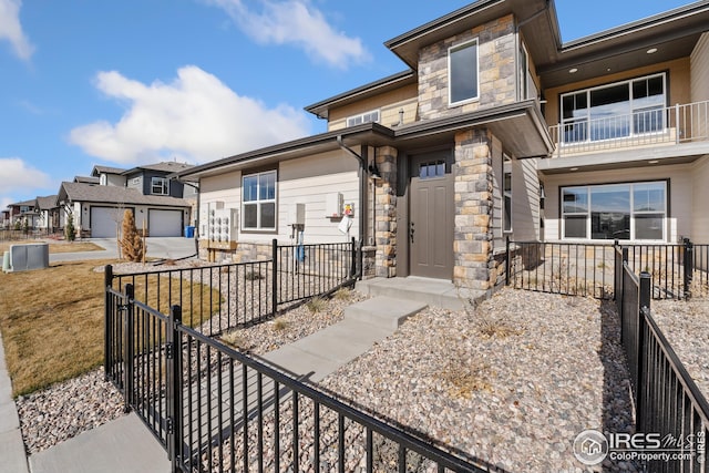 938 Schlagel St Unit 7, Fort Collins, CO 80524 - view of front of house with stone siding, a balcony, a garage, and fence