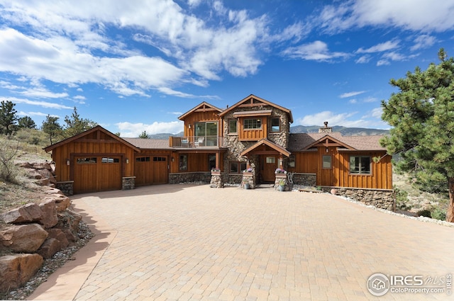 chalet / cabin featuring a garage, a balcony, stone siding, decorative driveway, and board and batten siding