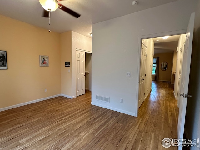 unfurnished bedroom with visible vents, ceiling fan, baseboards, and wood finished floors