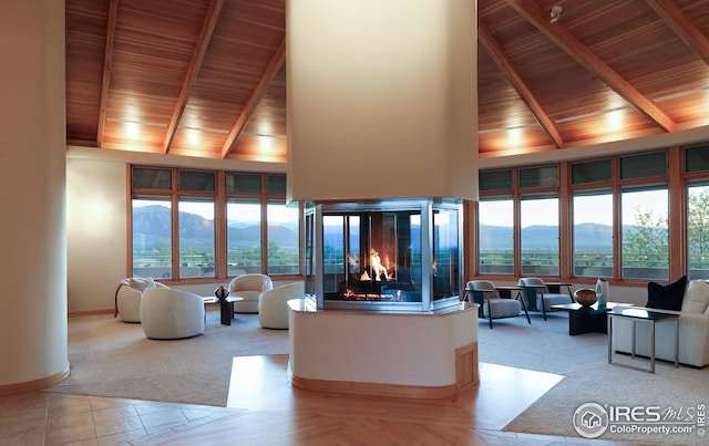 carpeted living room with a multi sided fireplace, a mountain view, wooden ceiling, and high vaulted ceiling