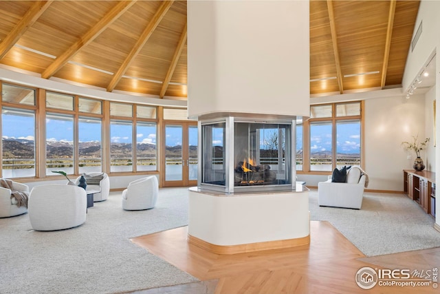 living room featuring a multi sided fireplace, a water view, and wood ceiling