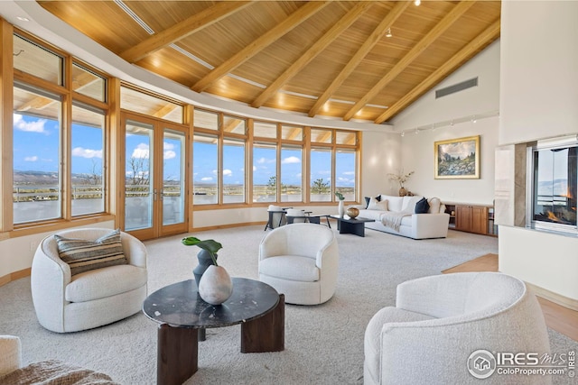 living room with wood ceiling, beam ceiling, high vaulted ceiling, a water view, and carpet flooring