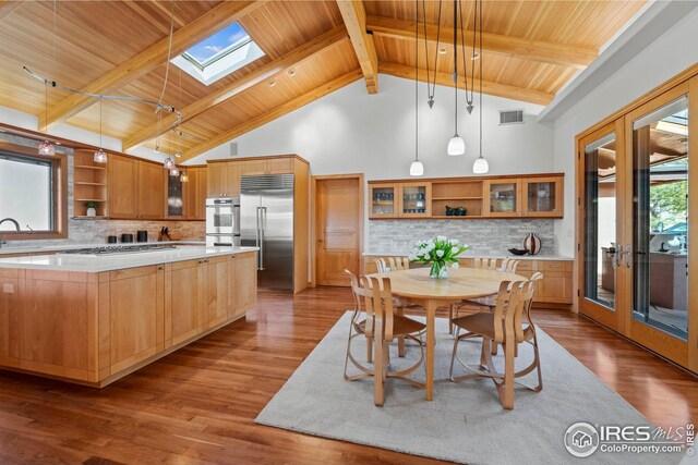 kitchen with french doors, decorative light fixtures, a skylight, appliances with stainless steel finishes, and a kitchen island