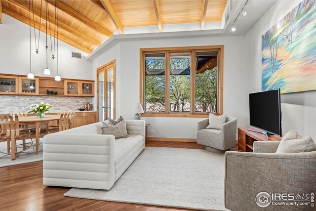 living room with lofted ceiling with beams, rail lighting, wooden ceiling, and dark hardwood / wood-style flooring