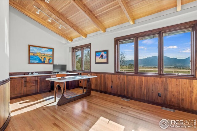 office space with wooden walls, lofted ceiling with beams, rail lighting, wooden ceiling, and light wood-type flooring