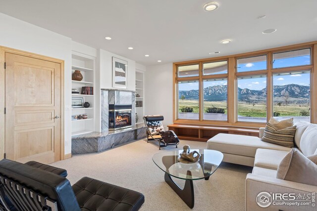 carpeted living room with a mountain view, a fireplace, and built in features