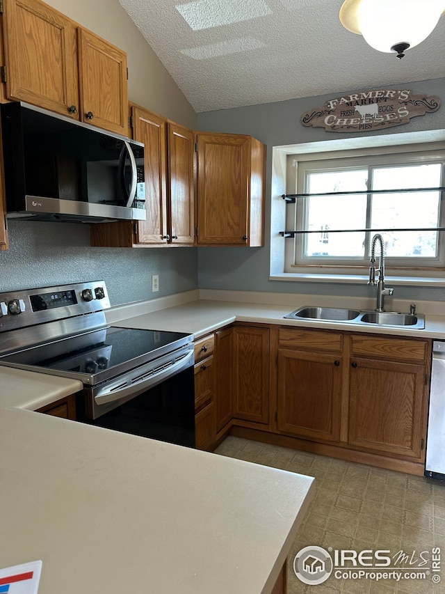 kitchen with sink, dishwasher, a textured ceiling, vaulted ceiling, and stainless steel range with electric cooktop