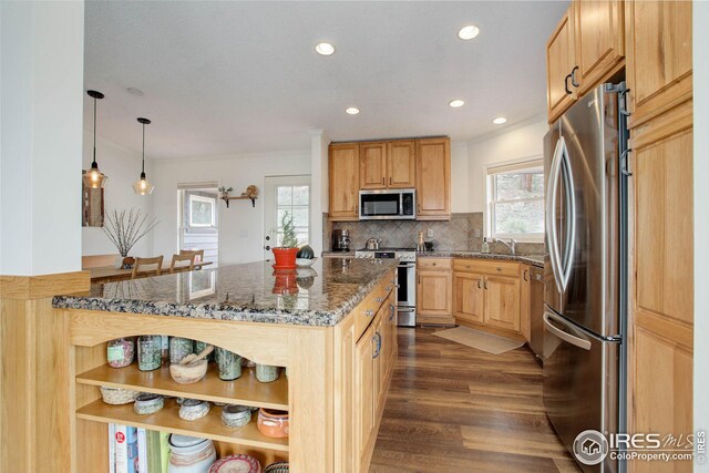 kitchen with dark stone countertops, dark wood-style floors, stainless steel appliances, crown molding, and backsplash