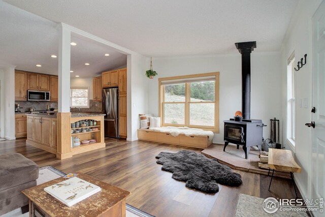 living room featuring recessed lighting, dark wood finished floors, a wood stove, and crown molding